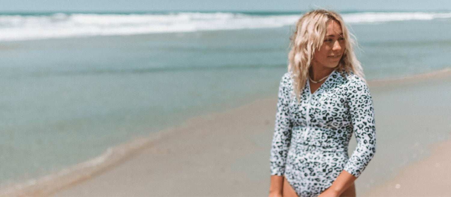 Model surfing in a Midori surf suit with long sleeves, cutout sides, and cheeky coverage—showcasing secure, eco-friendly swimwear.